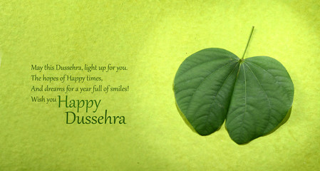 Indian Festival Dussehra, showing golden leaf and flowers on green background. Greeting card.
