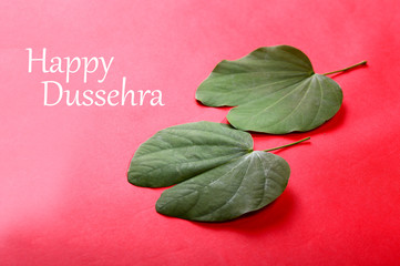 Indian Festival Dussehra, showing golden leaf on red background. Greeting card.