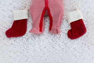 Newborn legs with red Christmas socks on a white blanket as a background