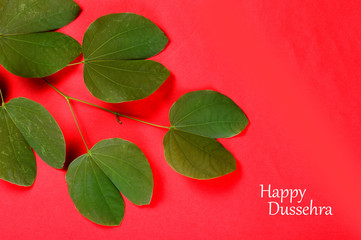 Indian Festival Dussehra, showing golden leaf on red background. Greeting card.