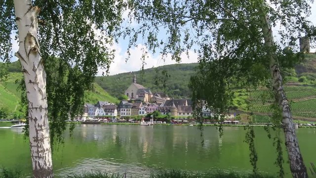 cityscape of Beilstein at Moselle River with motorboat passing by on river.