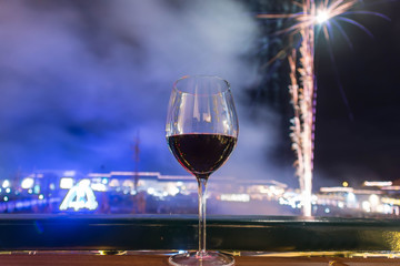 Glass of red wine with fireworks in Villa de Leyva main square in the background