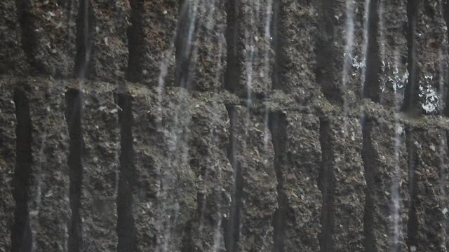 Rain drops and hailstones falling and dripping on plaster and building bricks during a thunderstorm.