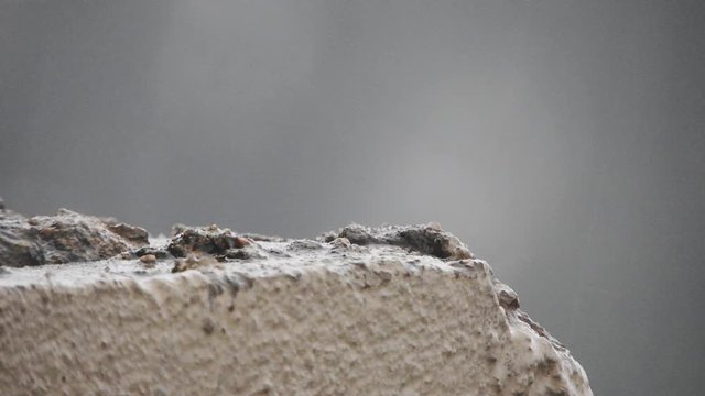 Rain drops and hailstones falling and dripping on plaster and building bricks during a thunderstorm.