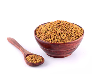 Fenugreek seeds in wooden bowl with spoon isolated on white background