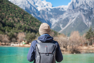 Young man traveler traveling at Blue Moon Valley, landmark and popular spot inside the Jade Dragon Snow Mountain Scenic Area, near Lijiang Old Town. Lijiang, Yunnan, China. Solo travel concept - obrazy, fototapety, plakaty