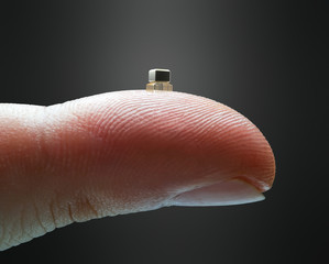 Tiny microchip on the fingertip. Finger holding a miniaturized microchip. Technology concept and...