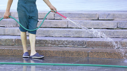 worker from a hose watering the city street