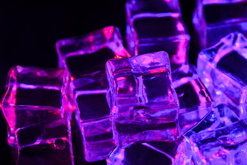 Ice cube. Close-up of melting ice cubes with pink and purple illumination on a black background. Macro horizontal photography