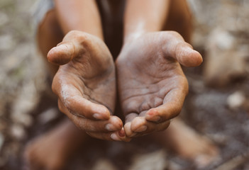 poor child or beggar begging you for help sitting at dirty slum. concept for poverty or hunger...