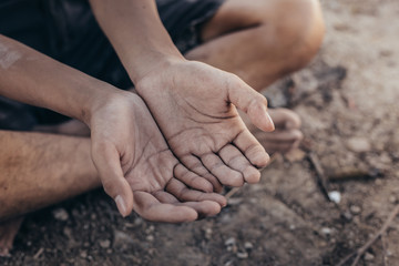 poor child or beggar begging you for help sitting at dirty slum. concept for poverty or hunger people,human rights,donate and charity for underprivileged children in third world