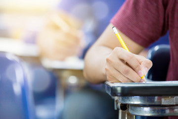 high school,university student study.hands holding pencil writing paper answer sheet.sitting lecture chair taking final exam attending in examination classroom.concept scholarship for education abroad