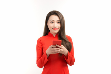 An asian cute woman in vietnamese dress is using mobile phone for chatting