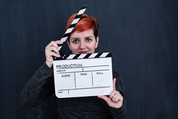 redhead woman holding movie clapper