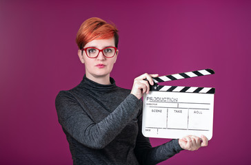 woman holding movie clapper isolated on pink background