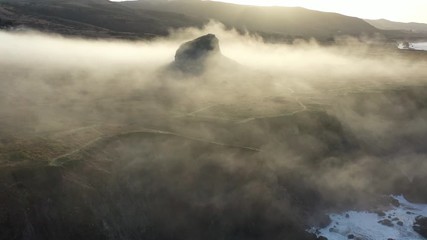 Morning mist flows past a massive rocky outcrop rising from the coast of northern California. The coastal region north of San Francisco is very scenic and accessible from the Pacific Coast highway.