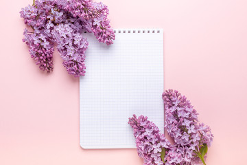Lilac and notepad on pink background. Still life. Spring romantic mood. Top view. Copy space