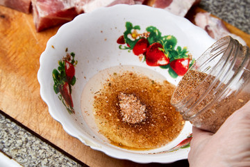 Cooking. Pouring spices from glass bottle into a plate with sunflower oil