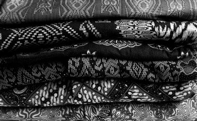 Stack of batik with various motives in gray scale or monochrome