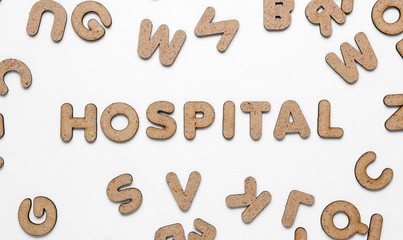 The word hospital among many wooden letters on white background. Top view