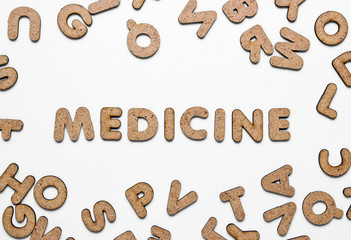 The word medicine among many wooden letters on white background. Top view