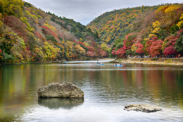 Kyoto, Japan - November 26, 2019: Local people and tourist riding boat at Hozu river in Autumn season at Arashiyama area in Kyoto, Japan