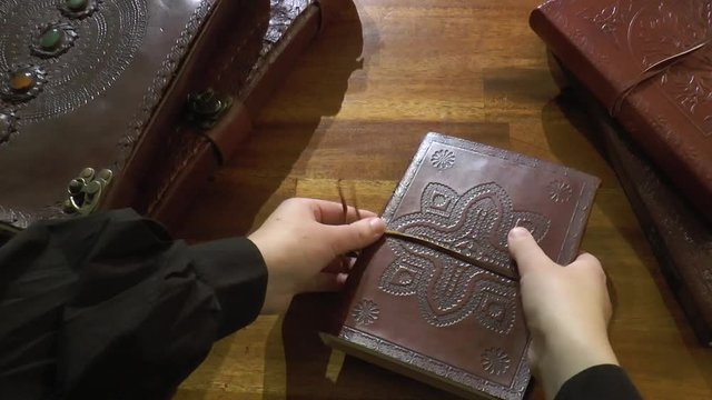 A woman opens a leather journal - top view, no candle
