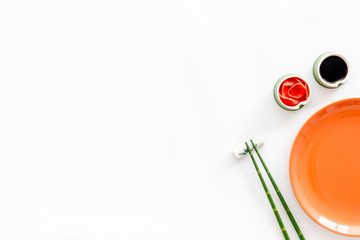 Tableware for sushi and rolls. Plate, chopsticks, bowls with ginger and sause on white background top-down copy space