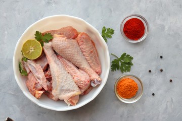Clean and Raw Free range or country chicken carved in parts in a bowl with Indian spices and cooking ingredients. Along with copy space