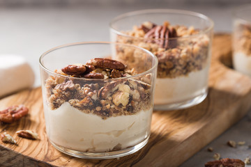 Delicious natural yogurt parfait with caramel, pecan nuts on conctere background