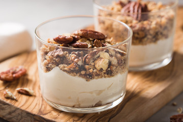 Delicious natural yogurt parfait with caramel, pecan nuts on conctere background