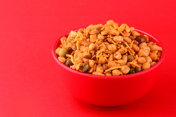 Indian Snacks : Mixture (roasted nuts with salt pepper masala, pulses, channa masala dal, green peas) in red bowl on red background