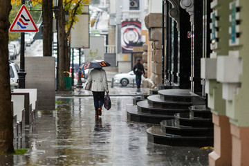 Fototapeta premium Rainy weather in the city. People walk under umbrellas during light rain on the wet streets of the city.