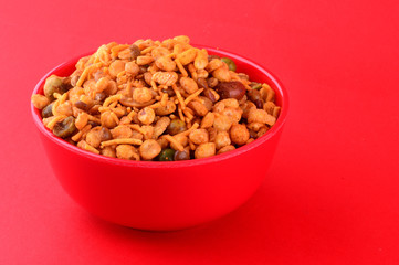 Indian Snacks : Mixture (roasted nuts with salt pepper masala, pulses, channa masala dal, green peas) in red bowl on red background