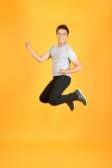 Fototapeta na wymiar Full length portrait of an excited young man in white t-shirt jumping while celebrating success isolated over orange background