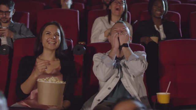 Tracking shot of group of people watching comedy and laughing at the movies