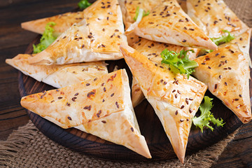 Asian food. Samsa (samosas) with chicken fillet and cheese on wooden background.