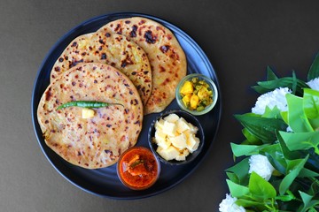 Indian Food - Aloo Paratha or Indian Potato stuffed Flatbread. Served with butter for breakfast, pickle and masala potatoes among with Indian Tea or masala chai.  with copy space.