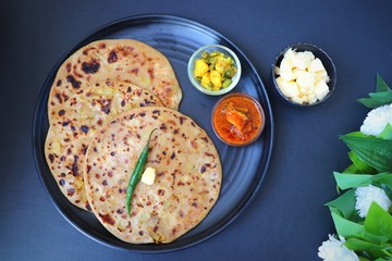 Indian Food - Aloo Paratha or Indian Potato stuffed Flatbread. Served with butter for breakfast, pickle and masala potatoes among with Indian Tea or masala chai.  with copy space.