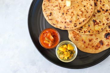 Indian Food - Aloo Paratha or Indian Potato stuffed Flatbread. Served with butter for breakfast, pickle and masala potatoes among with Indian Tea or masala chai.  with copy space.