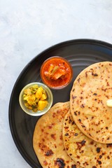Indian Food - Aloo Paratha or Indian Potato stuffed Flatbread. Served with butter for breakfast, pickle and masala potatoes among with Indian Tea or masala chai.  with copy space.