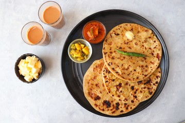 Indian Food - Aloo Paratha or Indian Potato stuffed Flatbread. Served with butter for breakfast, pickle and masala potatoes among with Indian Tea or masala chai.  with copy space.