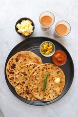 Indian Food - Aloo Paratha or Indian Potato stuffed Flatbread. Served with butter for breakfast, pickle and masala potatoes among with Indian Tea or masala chai.  with copy space.