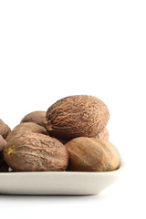 Nutmeg in white plate isolated on white background