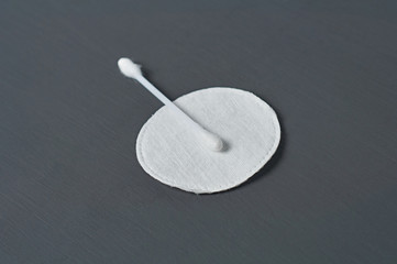 One clean cotton stick and pad lies on dark concrete desk. Close-up