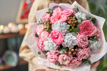 European floral shop. Beautiful bouquet of mixed flowers in womans hands. the work of the florist at a flower shop. Delivery fresh cut flower.