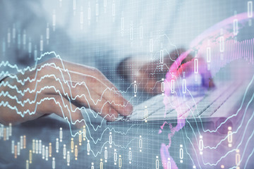 Double exposure of graph with man typing on computer in office on background. Concept of hard work.