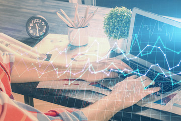 Double exposure of stock graph with businessman typing on computer in office on background. Concept of hard work.