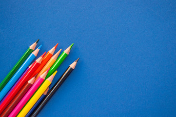Colorful pencils on blue background with copyspace. 2020 color trend.
