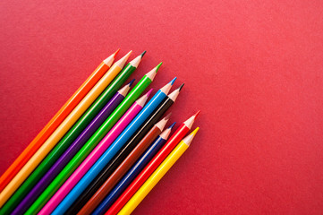 Fototapeta premium Colorful pencils on red background with copyspace.